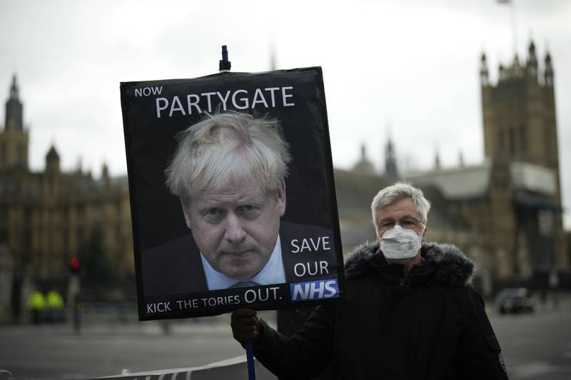 An anti-government protester with an image of British Prime Minister Boris Johnson including the words 'Now Partygate'. AP