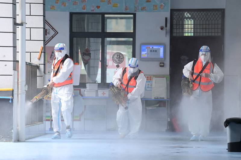 Staff members spray disinfectant at a primary school in Wuhan, China.  AFP