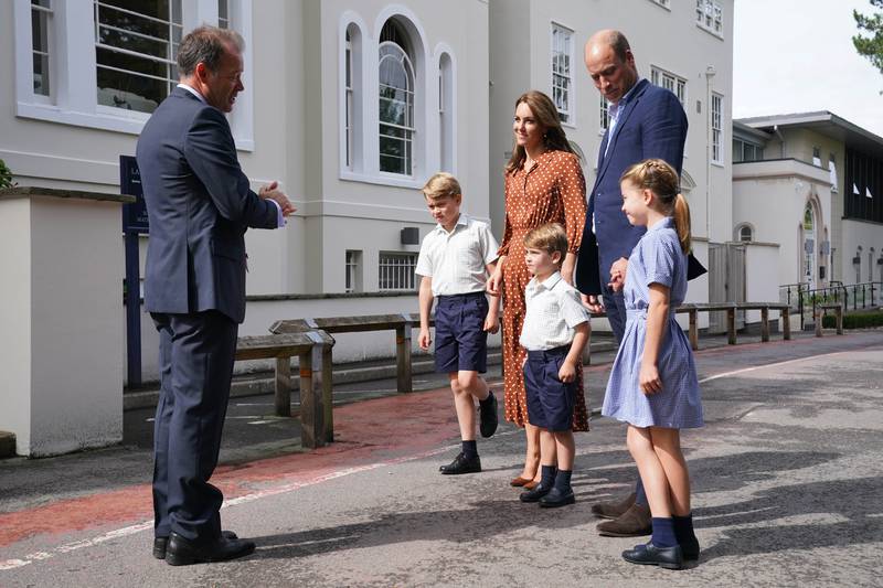 Mr Perry greets the royals at the door of his school. PA