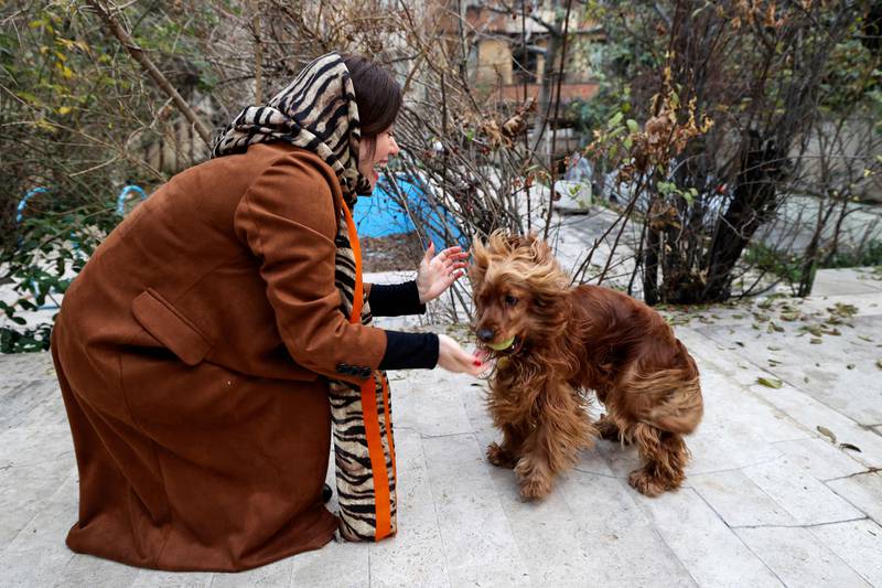A woman plays with her dog in a yard near her house in northern Tehran.