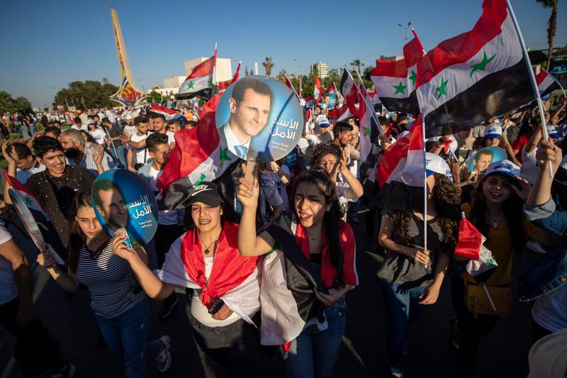 Bashar Al Assad supporters hold up national flags and pictures of the president. He is campaigning on the pledge to reconstruct the country, which has been devastated by a decade-long civil war. AP Photo