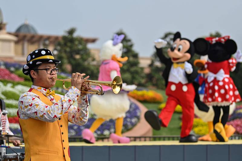 A musician performs and Disney characters dance during the reopening of Shanghai Disneyland on May 11, 2020. AFP