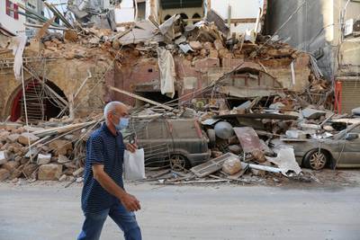 A man walks past damaged building and vehicles near the site of Tuesday's blast in Beirut's port area. Reuters