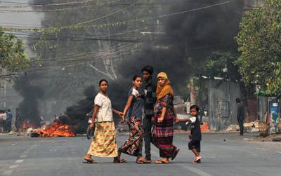People walk on a street as barricades burn behind them in Mandalay. reuters