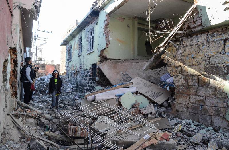 Boys walk among rubble and damaged buildings in the Sur district in Diyarbakir on December 11, 2015.
A policeman was killed on December 9, 2015 by sniper fire as he tried to defuse an explosive device in the Sur district of Diyarbakir province, which has been under military curfew for eight days. Turkey has been waging a relentless offensive against PKK strongholds in the southeast of the country and in northern Iraq following the collapse in July of a two-year truce with rebels.   
 / AFP PHOTO / ILYAS AKENGIN