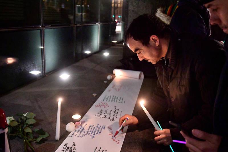 People write messages on a sheet of paper during a gathering at the New Zealand Embassy in Brussels. AFP