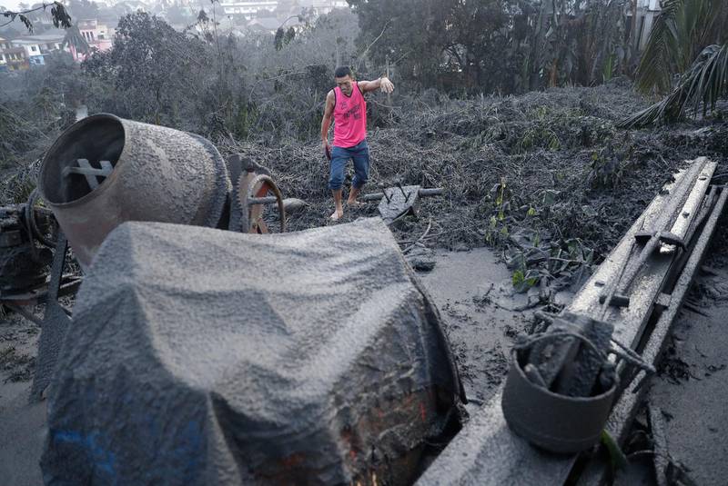 A man walks along ash fall covered plants and equipment as Taal Volcano continues to spew ash on Monday. AP Photo