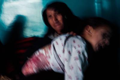 January 31st, 2019 - Kabul, Kabul, Afghanistan: Alia's grandmother and mother treat her wounds as Alia thrashes and screams in pain. Alia was burned by a teakettle as a result of the attack that happened at Green Village.

The attack on the Green Village, a compound in Kabul that houses foreign workers and NGO's, initially killed 9 and wounded over 120 Afghans who lived in the vicinity.

Alia is burned from the top of her back down to her knees. Treating and cleaning her wounds is excruciatingly painful.

Ivan Flores/The National