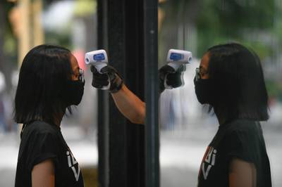A store employee measures the temperature of a woman before allowing her to enter the shop in Caracas, Venezuela. AP Photo