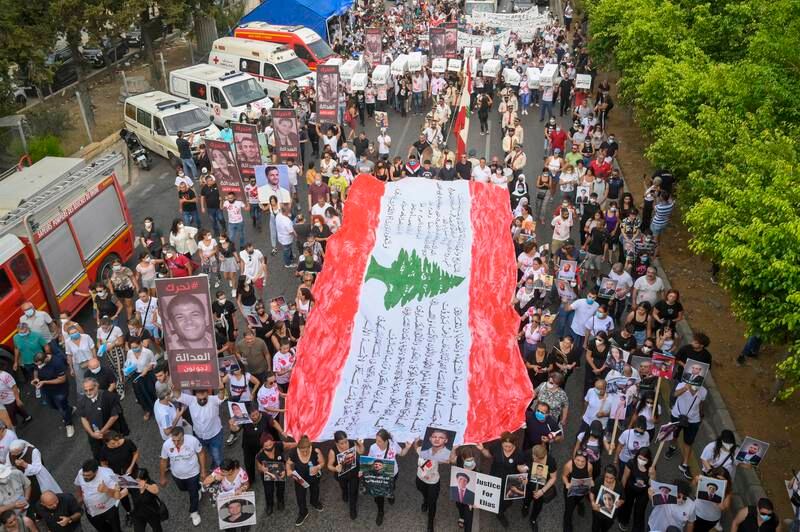 People hold the Lebanese flag during a march to the Beirut port. EPA