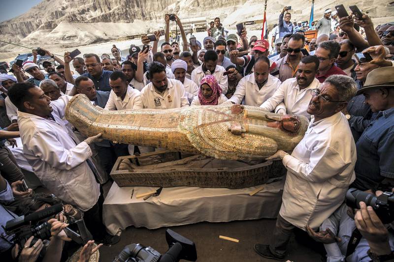 Egyptian archeologist open a wooden coffin belonging to a man in front Hatshepsut Temple at Valley of the Kings in Luxor on October 19, 2019. - Egypt revealed on Saturday a rare trove of 30 ancient wooden coffins that have been well-preserved over millennia in the archaeologically rich Valley of the Kings in Luxor. (Photo by Khaled DESOUKI / AFP)