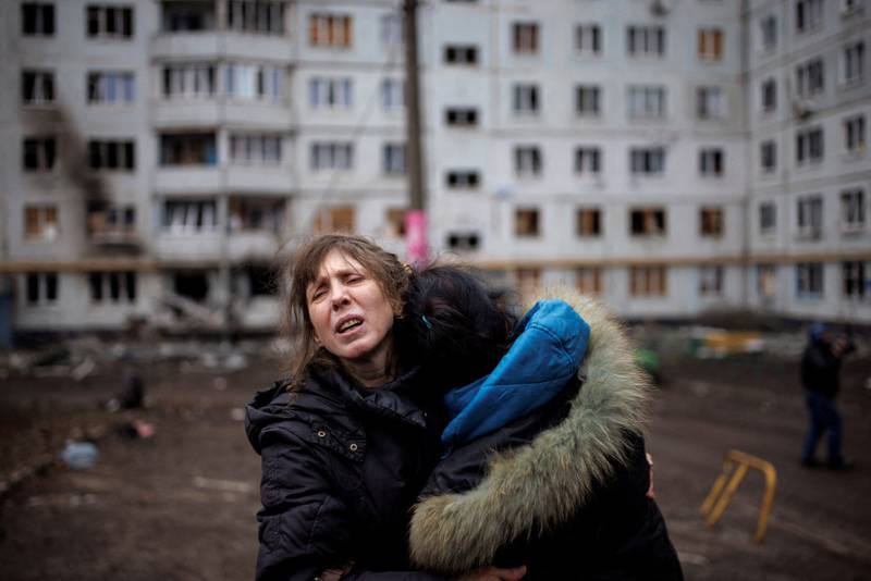 Two women hug outside a heavily damaged apartment block following an artillery attack in Kharkiv. Reuters