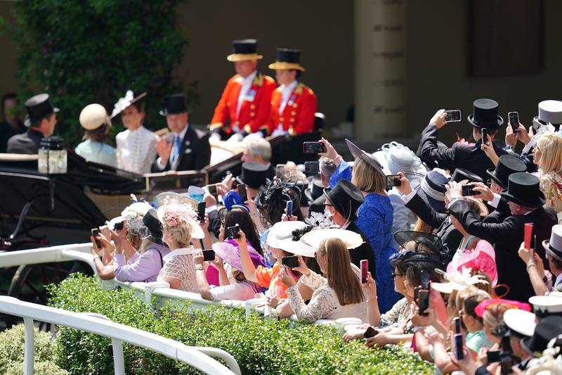 Racegoers take photos as the Duke and Duchess of Cambridge go past in a carriage. Getty Images