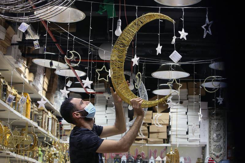 A vendor puts up stars and crescent moon decorations in his shop at a market in Kuwait City, Kuwait, the day before the start of Ramadan. AFP