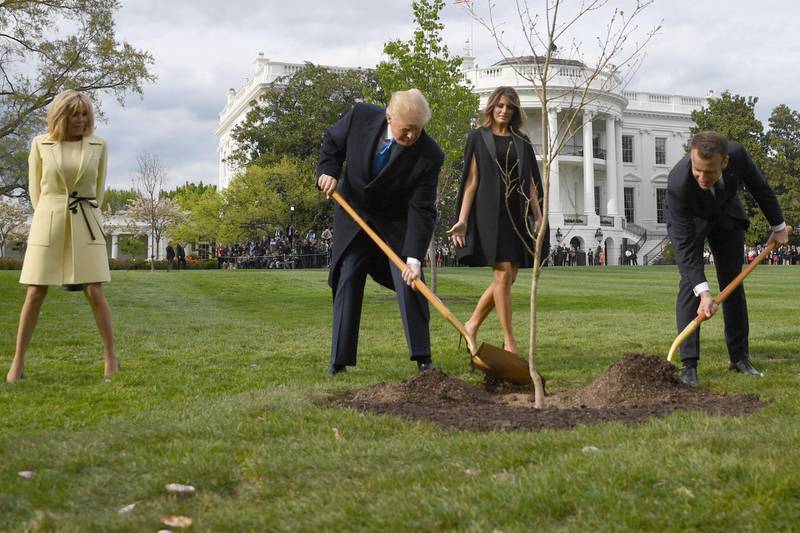 (FILES) In this file photo taken on April 23, 2018 US President Donald Trump and French President Emmanuel Macron plant a tree watched by Trump's wife Melania and Macron's wife Brigitte on the grounds of the White House in Washington,DC. The photo of Donald Trump and his French counterpart Emmanuel Macron planting an oak tree in the garden of the White House symbolized the friendship shown by the two leaders. But relations between them have since frayed -- over issues ranging from Iran to trade -- and the tree, a diplomatic source said this week, did not survive. / AFP / JIM WATSON
