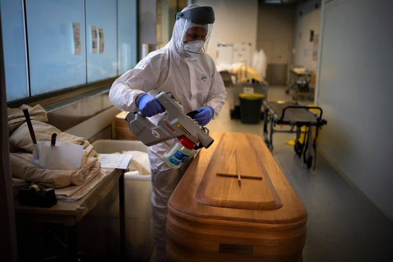 A mortuary worker disinfests a coffin carrying the body of a person who died of Covid-19 in Girona, Spain. Spain's health ministry said Wednesday that the nation has surpassed 60,000 fatalities. AP Photo