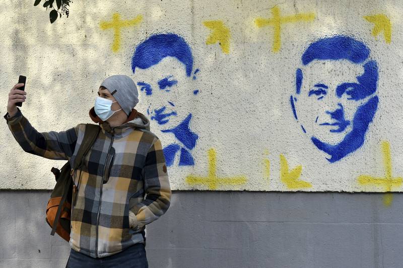 A man takes a selfie in front of murals of Kyiv mayor Vitali Klitschko and Ukraine's President Volodymyr Zelenskyy, in Podgorica, Montenegro, on March 8. AP