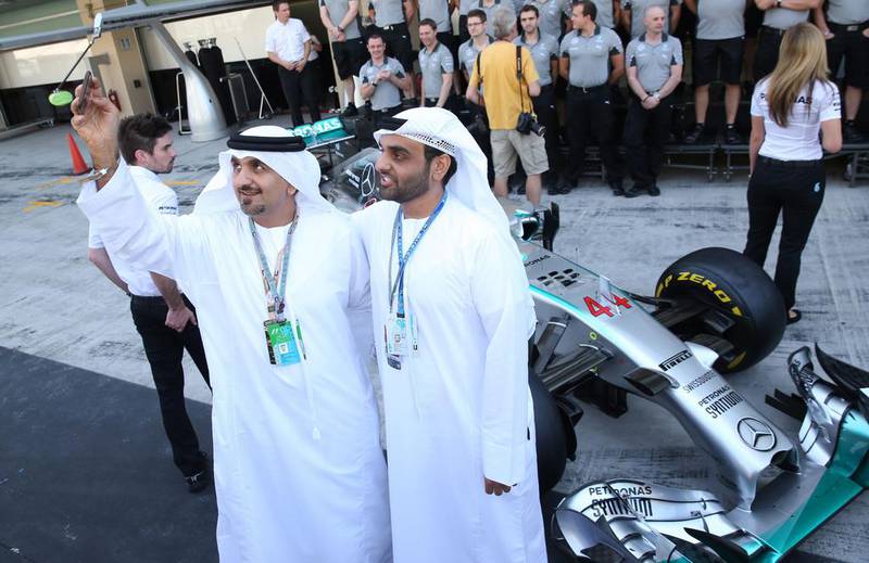 Two Emirati F1 fans take a selfie in front of Hamilton's car. Ali Haider /  EPA