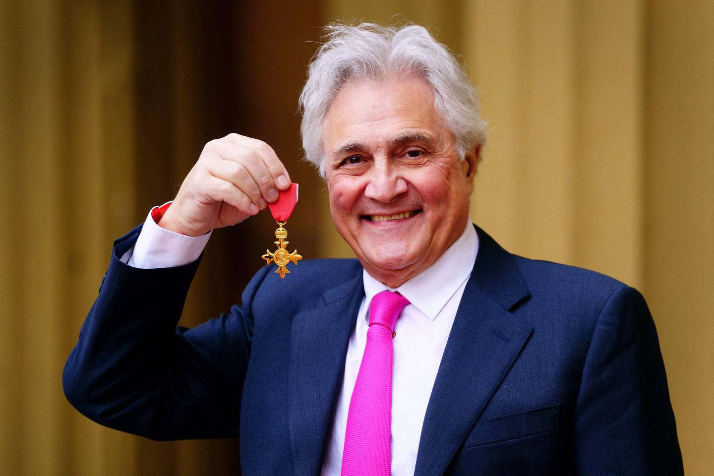 Le diffuseur anglais John Suchet pose avec une médaille après avoir été nommé Officier de l'Ordre de l'Empire britannique à la suite d'une cérémonie d'investiture au palais de Buckingham, dans le centre de Londres.  AFP