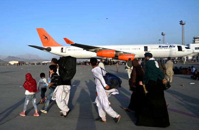 Afghan families walk past aircraft at Hamid Karzai International Airport as thousands try to flee the Taliban. Getty Images