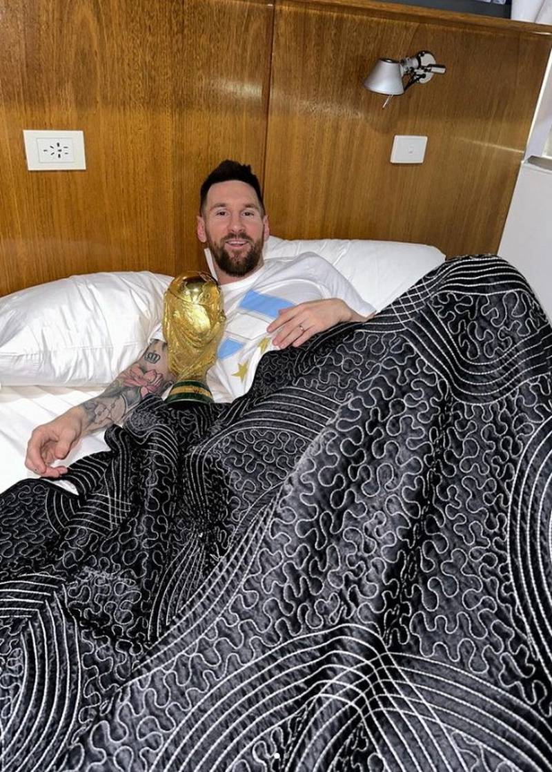 Argentina's Lionel Messi lies in bed with the Fifa World Cup trophy on Tuesday, December 20, 2022, after he and his teammates arrived in Buenos Aires to a heroes' welcome following their penalty shoot-out victory over France in the final in Qatar. Reuters