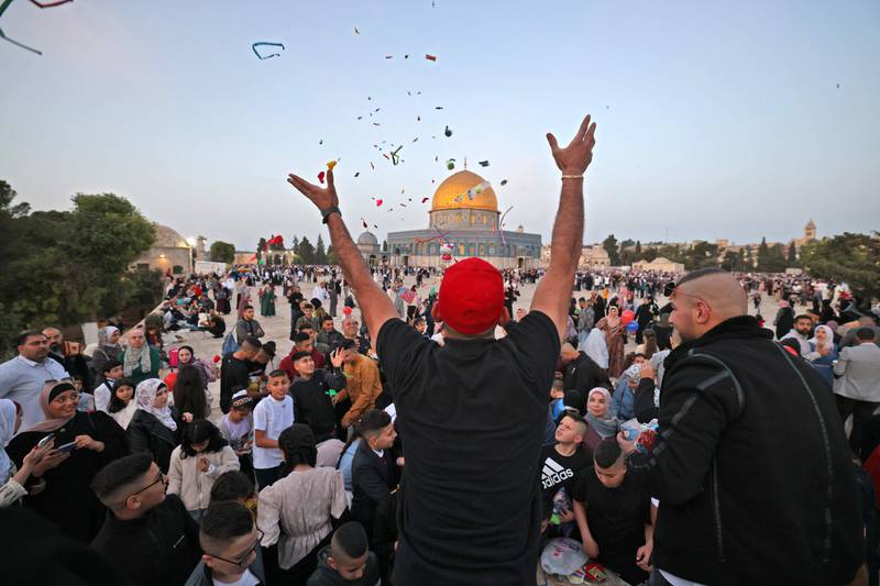 A Muslim man hands out sweets, with the Dome of the Rock mosque in the background, after morning Eid Al Fitr prayer at the Al Aqsa compound in Old Jerusalem. AFP