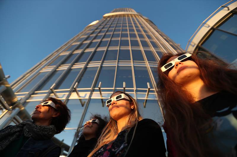 People wearing special glasses watch a partial solar eclipse from the 124th floor of the Burj Khalifa. EPA