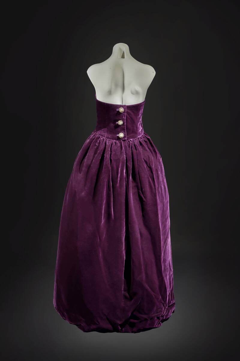 'A strapless, evening dress of deep aubergine silk velvet, with a tulip-shaped stiffened skirt, augmented by three paste buttons at the back... ' reads a description on the Sotheby's website