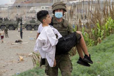 A Spanish soldier helps a migrant as troops are deployed along the coast in Ceuta. EPA