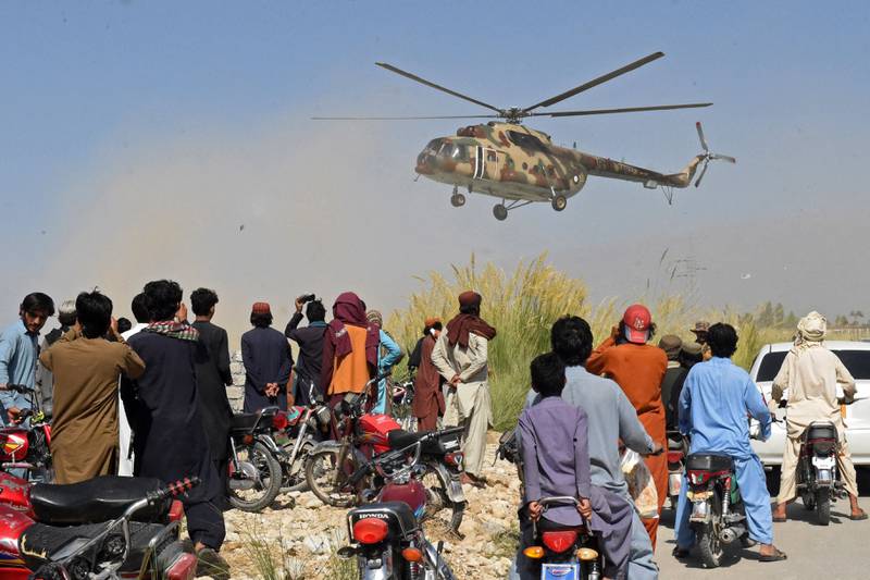 Residents watch as a Pakistani army helicopter carrying a rescue team prepares to land in the quake-hit Harnai. AFP