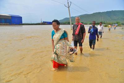 Villagers wade across a flooded road. AFP