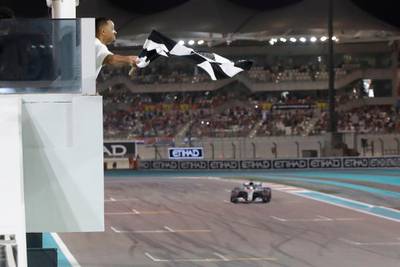 Will Smith waves the checkered flag as Mercedes' British driver Lewis Hamilton crosses the finish line during the Abu Dhabi Formula One Grand Prix at the Yas Marina Circuit yesterday.AFP