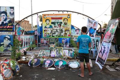A protester stands next to the pictures of protesters who were killed in clashes with security forces during the anti-government protests at Tahrir Square in central Baghdad. EPA