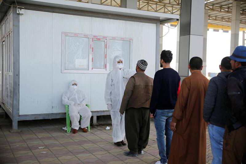 Members of the medical team check the temperature of Iraqi men, following the coronavirus outbreak, at the entrance checkpoint of South Mosul, Iraq.  Reuters
