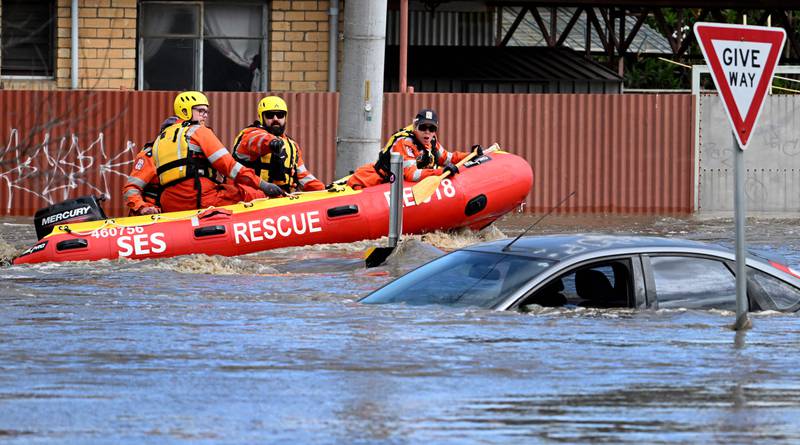 Emergency workers pass a submerged car on a flooded street in the Melbourne suburb of Maribyrnong. AFP