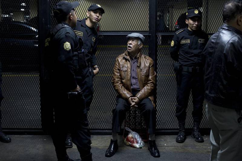 Edilberto Letona Linares, a former army officer, sits surrounded by police after arriving to a courtroom in Guatemala City. Moises Castillo / AP Photo