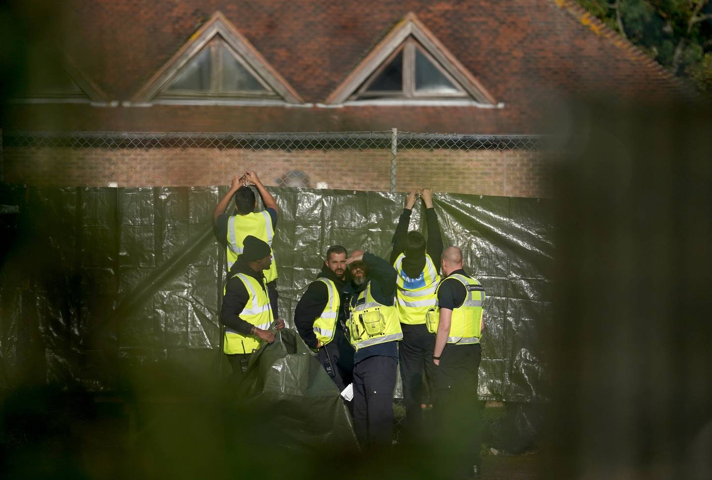 Security staff work to cover the view of people thought to be migrants at the Manston immigration short-term holding facility. PA 