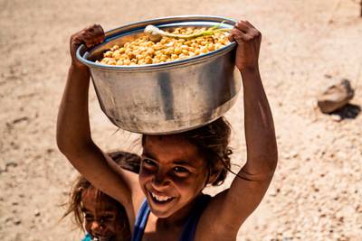 A displaced Syrian girl carries a pot of chickpeas at the Washukanni camp for the internally displaced in Syria's northeastern Hasakeh province, during  Ramadan. AFP