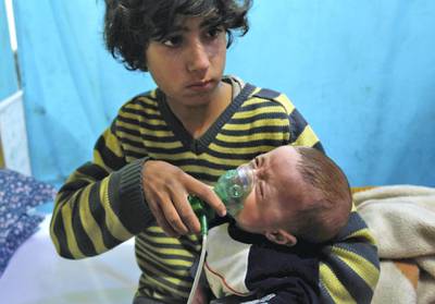 A Syrian boy holds an oxygen mask over the face of an infant at a make-shift hospital following a reported gas attack on the rebel-held besieged town of Douma in the eastern Ghouta region on the outskirts of the capital Damascus on January 22, 2018. - At least 21 cases of suffocation, including children, were reported in Syria in a town in eastern Ghouta, a beleaguered rebel enclave east of Damascus, an NGO accusing the regime of carrying out a new chemical attack said. Since the beginning of the war in Syria in 2011, the government of Bashar al-Assad has been repeatedly accused by UN investigators of using chlorine gas or sarin gas in sometimes lethal chemical attacks. (Photo by HASAN MOHAMED / AFP)