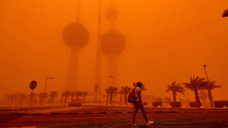 A man walks past the Kuwait Towers shrouded in heavy dust in Kuwait City. EPA