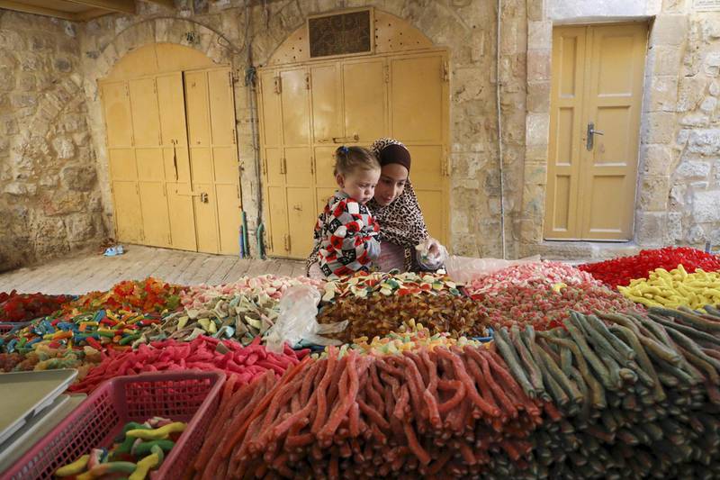 A Palestinian girl and her sibling shop for candy in the old city of the West Bank town of Hebron, during Muslim holy month of Ramadan.  AFP