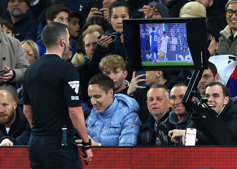 Referee Michael Oliver looks at the VAR monitor before awarding a penalty and showing a red card to Tottenham Hotspur's Cristian Romero. Reuters