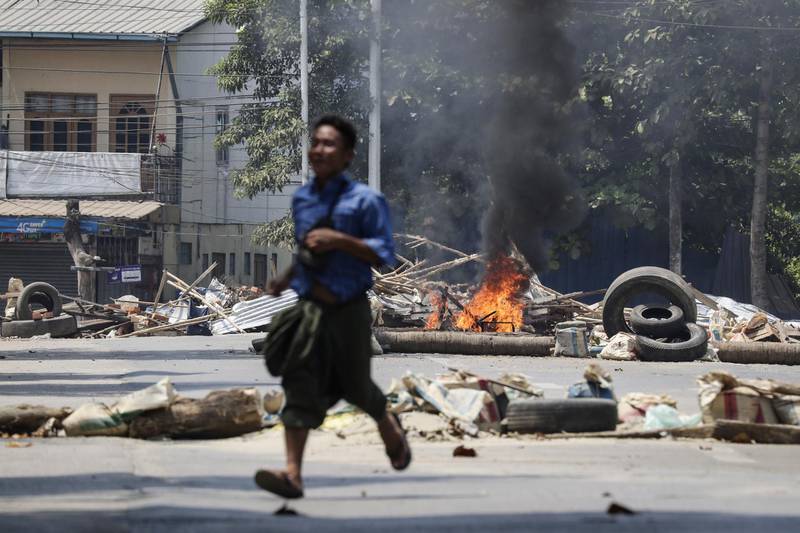 A man runs away from burning a roadblock, set on fire by military personnel at a railway staff compound during a raid against anti-coup activists, in Yangon, Myanmar. EPA