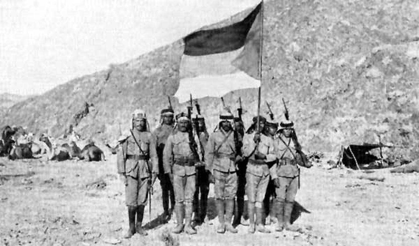Arab soldiers carry the flag of the Arab Revolt of 1916-1918 in the Arabian desert.