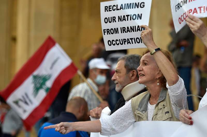 Lebanese anti-government protesters carry placards during a rally to mark the two-year anniversary of the beginning of the anti-government protest movement, in Beirut, on 17 October 2021. EPA