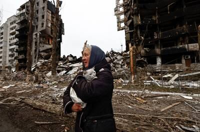 A woman carries her cat as she walks past buildings destroyed by Russian shelling in Borodyanka, Ukraine, on April 5. Reuters