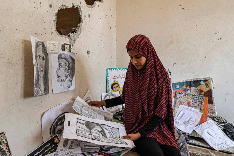 The sister of Palestinian artist Diana al-Amour, 22, who was reportedly killed in an Israeli bombardment days before, looks through her sketches in her room at the family home near the border with Israel, east of Khan Yunis in the southern Gaza Strip. AFP