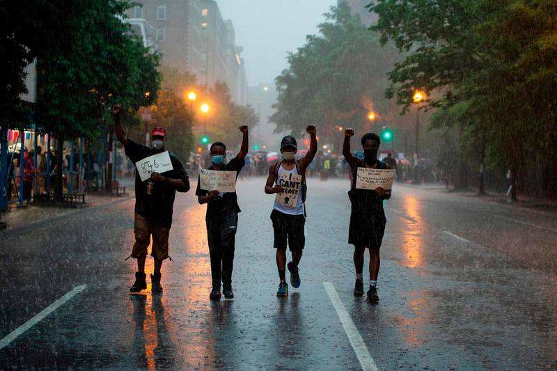 From left, Quacy, Quintan, both 12, Milo, and Quacy Jr, both 16 hold placards as they walk in the rain after attending a Black Lives Matter protest in front of Lafayette Park, near the White House, Washington DC.  AFP
