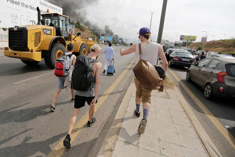 Passengers walk to the airport after anti-government protesters blocked the road. AP Photo