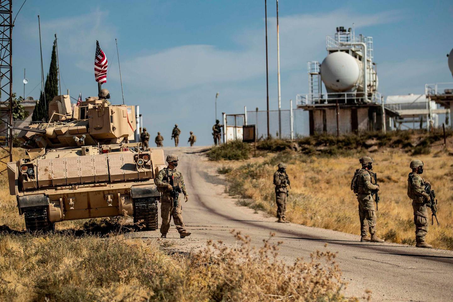 US soldiers walk near a Bradley Fighting Vehicle (BFV) during a military patrol by oil production facilities in the countryside near al-Malikiyah (Derik) in Syria's northeastern Hasakah province on October 27, 2020.  / AFP / Delil SOULEIMAN
